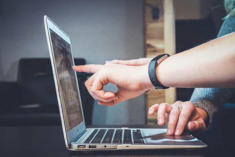 Two people pointing at a laptop screen analyzing the results of a parallel coordinate plot.